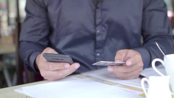 A mobiltelefont és hitelkártyát használó férfi kezek közelképe. — Stock videók