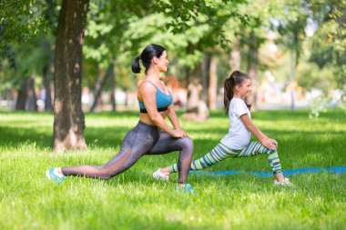 Anne ve kızı şehir parkında birlikte çalışıyor.