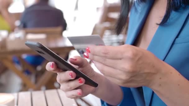 Visualizzazione ravvicinata di una mano femminile con telefono cellulare e carta di credito. — Video Stock