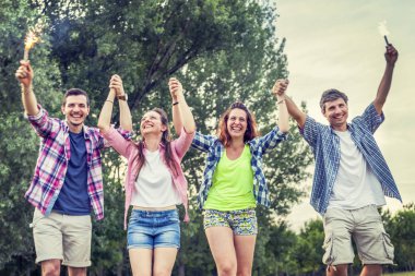 Grup arkadaşlar açık havada yaz sunset bulvarında eğleniyor, kıvılcım sopa ellerinde tuttukları