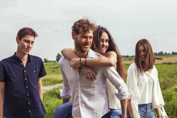 group of young handsome people walk together laughing on a country road in the summer