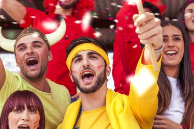 bir stadyum standları bir spor olayı izlerken çeşitli renklerde giyinmiş hayranları grup