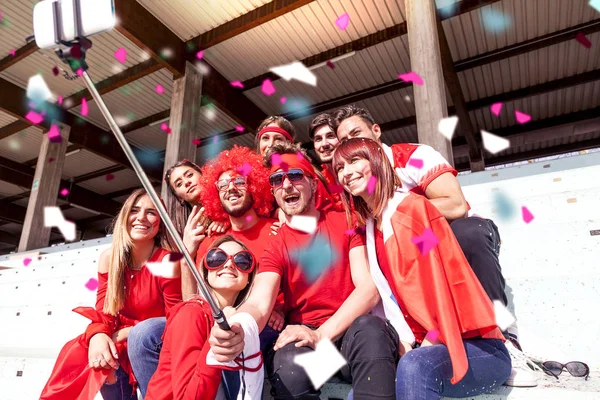 赤い色に身を包んだファンのグループは スポーツ イベントの間に競技場のスタンドで Selfie — ストック写真