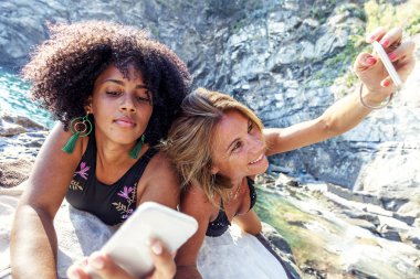 Sahilde cep telefonuyla farklı etnik yapı güzel kadınlarla birkaç. Smartphone - teknoloji kavramı bağımlısı gençler.