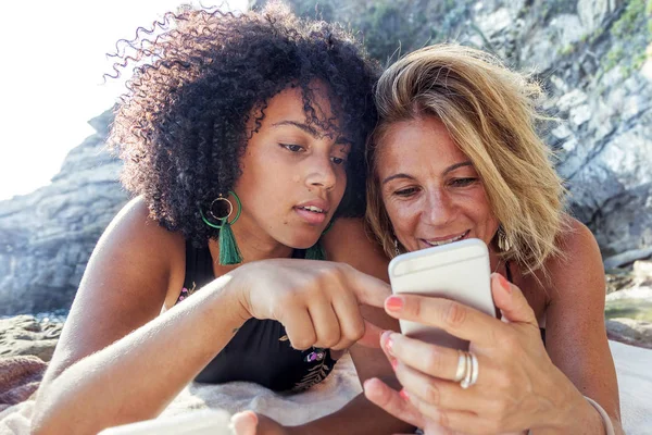 Coppia Belle Donne Diversa Etnia Utilizzando Telefono Cellulare Sulla Spiaggia — Foto Stock