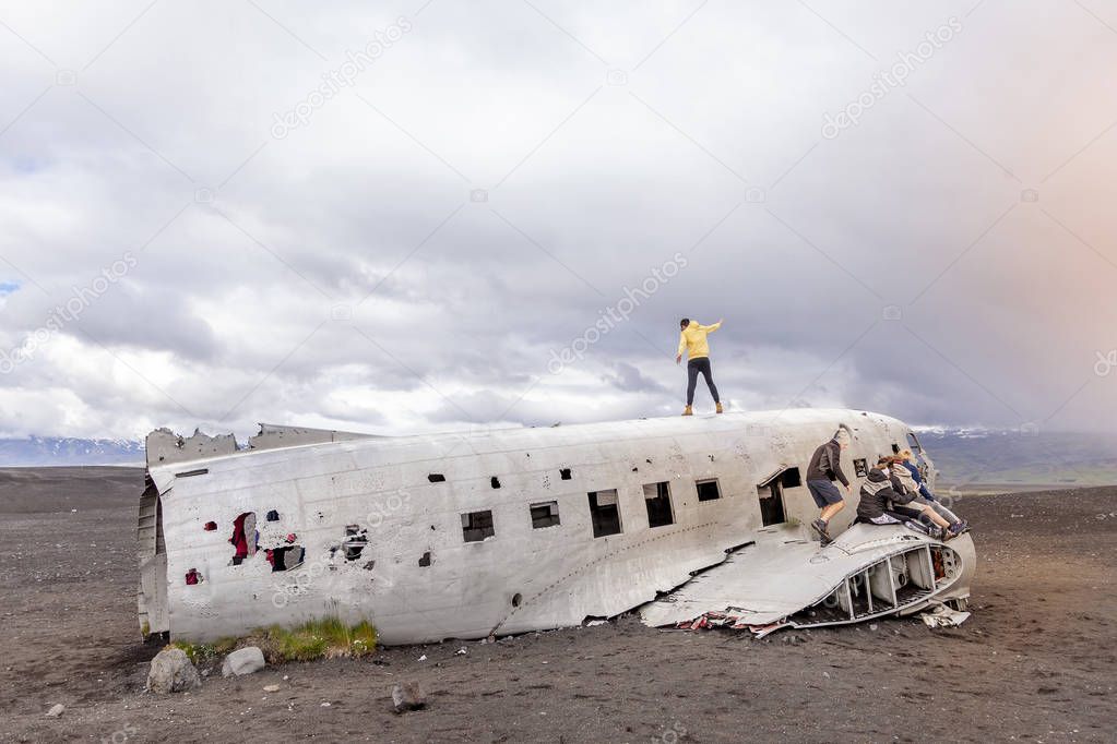 group of friends having fun walking over the wreck of a plane in Iceland
