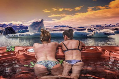 Çift bayanlar eğleniyor ve İzlanda'daki buzul önünde açık sıcak küvet avantajlarından tatil