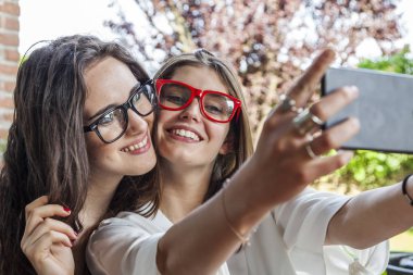iki genç arkadaşlar birlikte açık havada sarıldı komik yüzleri ile bir selfie almak
