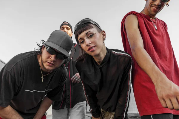 group of rappers posing on the metal rooftops of an abandoned building