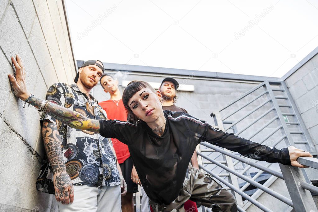 group of young rappers posing on the metal stairs of an abandoned building