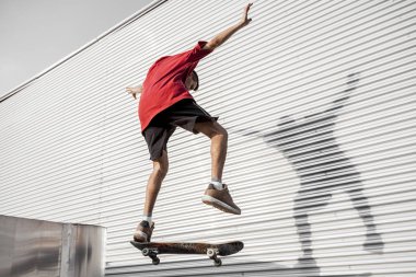 Genç kaykaycı kadar metal arka plan önünde onun yönetim kurulu ile terk edilmiş bir binada çatıların üzerinde atlar