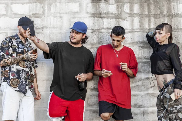 Grupo Amigos Tatuados Que Utilizan Teléfono Inteligente Contra Una Pared — Foto de Stock