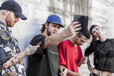 Grup dövmeli arkadaşıyla bir çatı - genç insanlar tarafından hareket eden smartphone - teknoloji millennials kavramı bağımlısı üzerinde gri bir duvara akıllı telefon kullanma