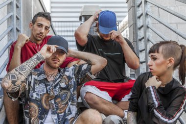 group of young rappers posing sitting on the metal stairs of an abandoned building clipart