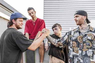 two friends rappers shaking hands against the wall on the metal rooftops of an abandoned building clipart