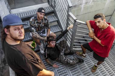 group of young rappers posing on the metal stairs of an abandoned building clipart