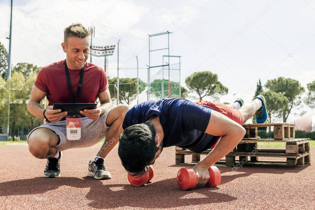 young athlete while exercising doing push-ups on the arms in an outdoor sports stadium
