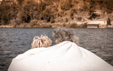 güzel Olgun çift iskelede oturup rahatlatıcı bir kış gününde bir battaniyeye sarılmış