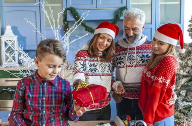 küçük çocuk evde onun Noel hediyesi alırken bir masada oturan