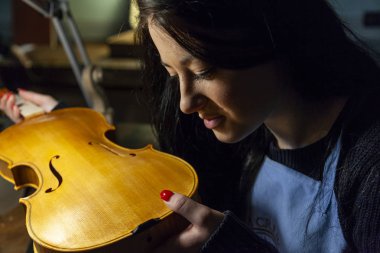 Genç kadın çırak violinmaker onun keman güzelliği kontrol