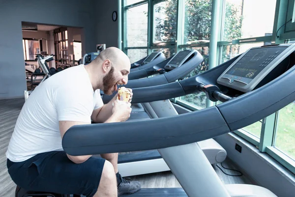 runner athlete while relaxing eating an ice cream on the driving machinery in the gym