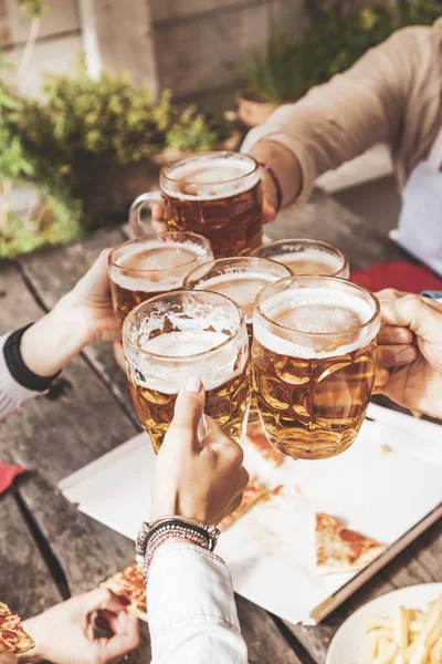 group of happy friends drinking beer and eating take away pizza