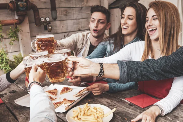 Mutlu arkadaş grubu bira içip pizza yiyor.