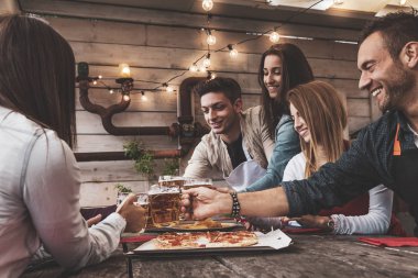 Mutlu arkadaş grubu bira içip pizza yiyor.
