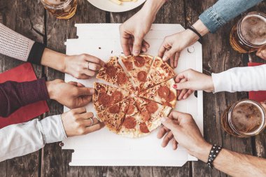 Mutlu arkadaşlar yemek pizza götürmek ve bira içme