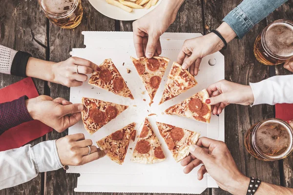 Gelukkige vrienden eten take-away pizza en bier drinken — Stockfoto