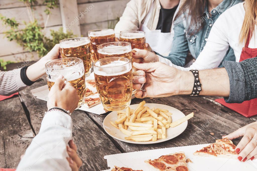 group of happy friends drinking beer and eating take away pizza