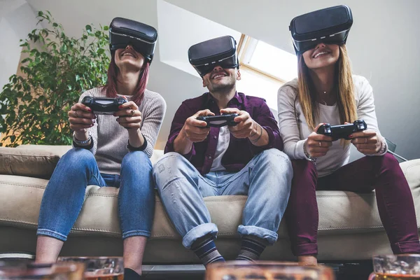 Młoda szczęśliwa trójka przyjaciół grająca w gry wideo wirtualna rzeczywistość — Zdjęcie stockowe