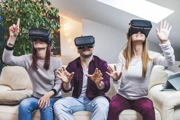 Joven feliz tres amigos jugando a los videojuegos de realidad virtual en — Foto de Stock