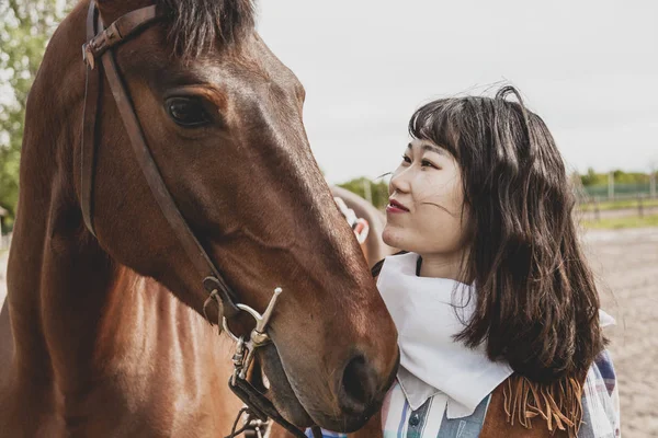 Linda vaquera china mientras cuida de su caballo —  Fotos de Stock