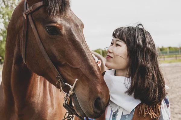 Cute chinese cowgirl while taking care of her horse — Stock Photo, Image