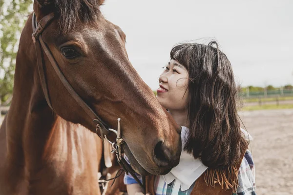 Cute chinese cowgirl while taking care of her horse — Stock Photo, Image