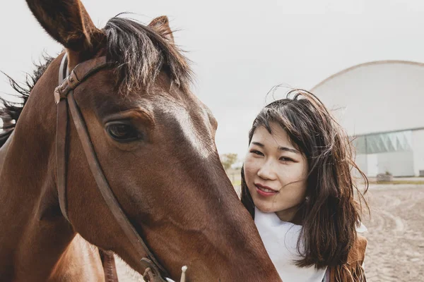 Cute chinese cowgirl while taking care of her horse — Stock Photo, Image