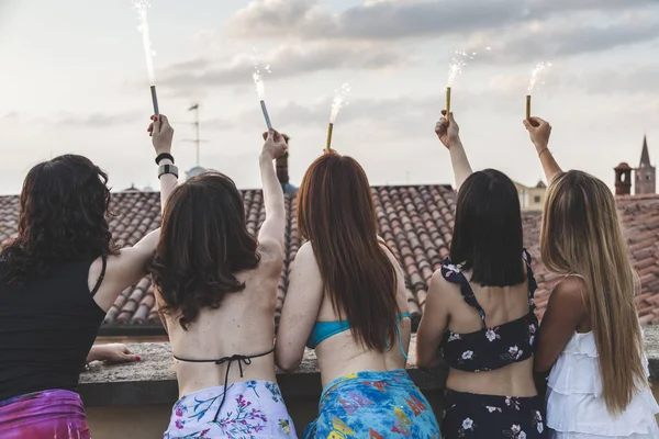 Gruppo di amiche felici che tengono scintille alla festa sul tetto — Foto Stock