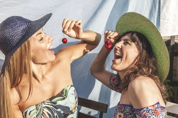 Casal amigos do sexo feminino se divertindo enquanto come cerejas no ro — Fotografia de Stock