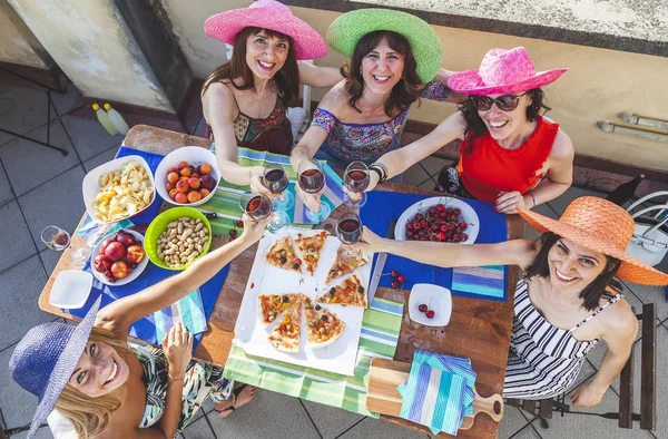 Gruppo di amiche che indossano cappelli colorati brindare con il rosso — Foto Stock