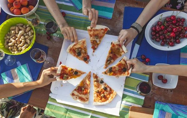 Kız arkadaşlarının elleri bir masadan pizza dilimleri paylaşmak — Stok fotoğraf