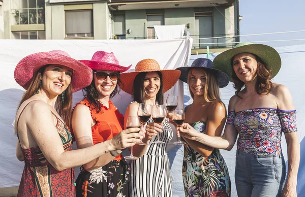 Ομάδα των γυναικών φίλων φορώντας καπέλα πρόποση κόκκινο κρασί — Φωτογραφία Αρχείου