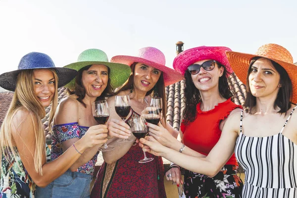 Ομάδα των γυναικών φίλων φορώντας καπέλα πρόποση κόκκινο κρασί — Φωτογραφία Αρχείου