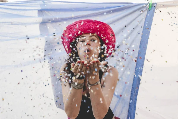 Bella donna con cappello di paglia colorato soffiando corietti — Foto Stock