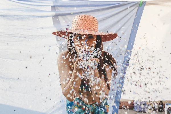 Bella donna con cappello di paglia colorato soffiando corietti — Foto Stock