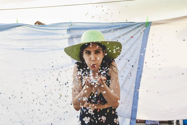 Bella donna con cappello di paglia colorato soffiando corietti — Foto Stock