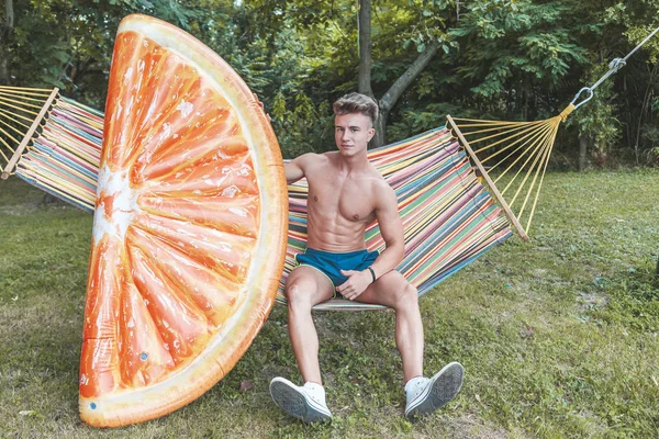 Joven musculoso adulto posando con una naranja en forma de rebanada de aire mate —  Fotos de Stock