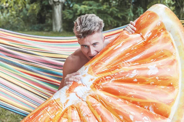 Joven musculoso adulto posando con una naranja en forma de rebanada de aire mate —  Fotos de Stock