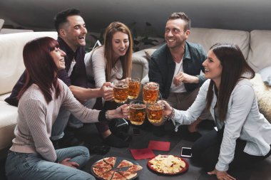 Mutlu arkadaş grubu bira içip pizza yiyor.