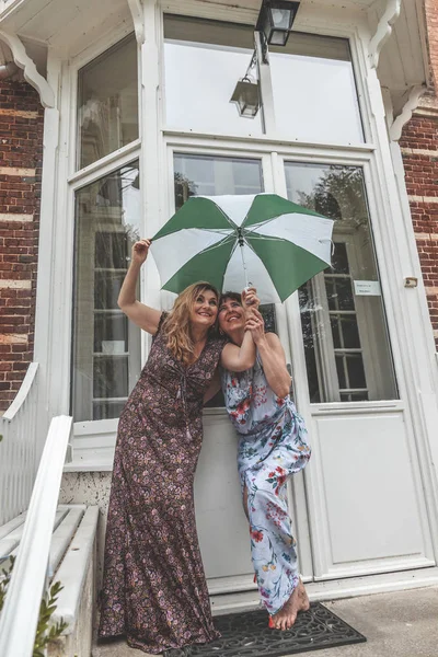 Couple of two attractive fifty year old women with umbrella — Stock Photo, Image